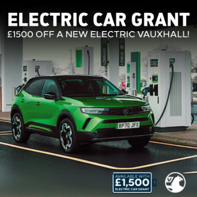 Green electric Vauxhall car parked at a charging station with grant offer text.
