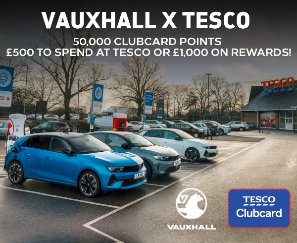 Vauxhall cars charging in Tesco car park with promotional Clubcard points offer displayed.